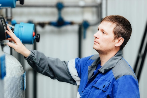 Um homem em roupas de trabalho verifica os sensores da caldeira ou estação do compressor Monitoramento do sistema