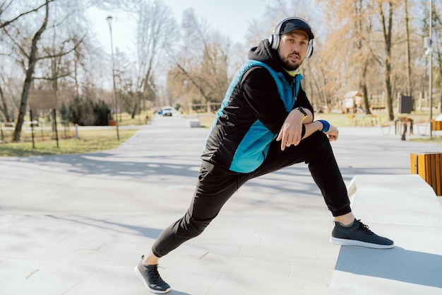 Um homem em roupas esportivas malha no parque pela manhã um atleta se prepara para correr