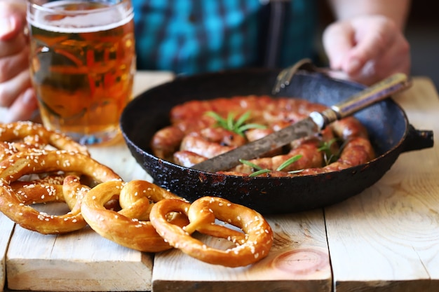 Um homem em um bar come linguiça e pretzels com cerveja. Menu da Oktoberfest.