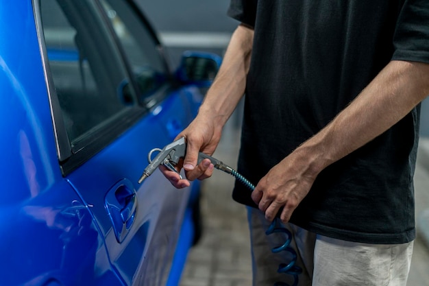 um homem em um lava-jato usa um compressor de ar para secar um carro