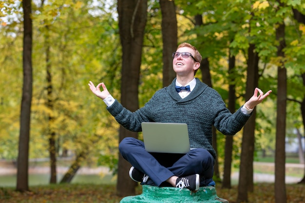 Um homem em um pedestal que finge ser uma estátua medita na posição de lótus no parque.