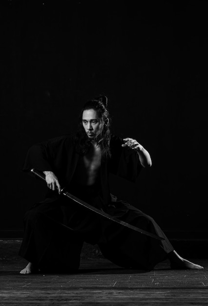 Um homem em um quimono preto com uma espada