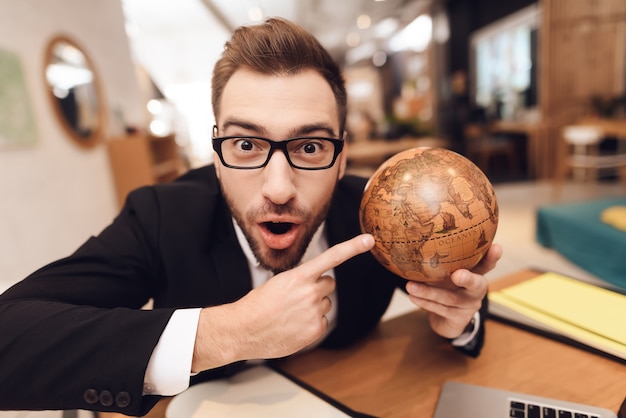 Um homem em um terno de negócio está segurando um globo nas mãos dele.