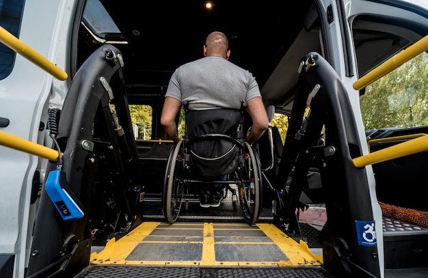 Um homem em uma cadeira de rodas em um elevador de um veículo para pessoas com deficiência.