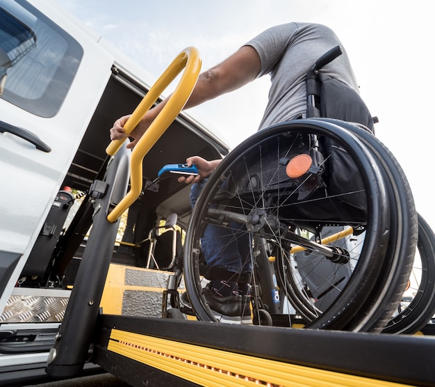 Um homem em uma cadeira de rodas em um elevador de um veículo para pessoas com deficiência.