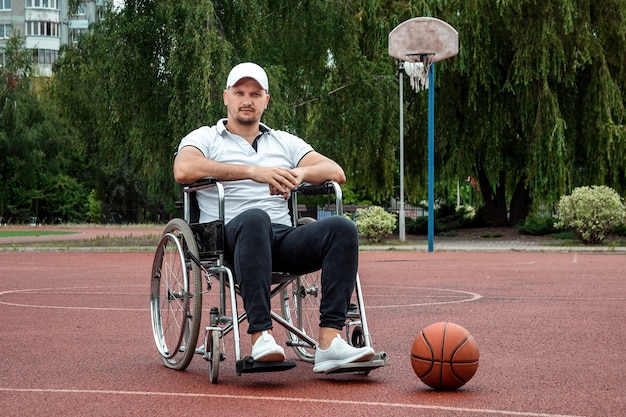 Um homem em uma cadeira de rodas joga basquete no campo de esportes. o conceito de uma pessoa com deficiência, uma vida plena, uma pessoa com deficiência, boa forma, atividade, alegria.
