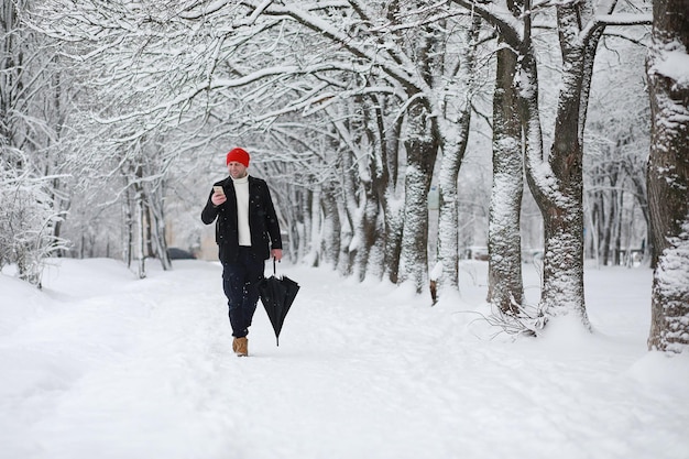 Um homem em uma caminhada no parque Jovem com a queda de neve do inverno