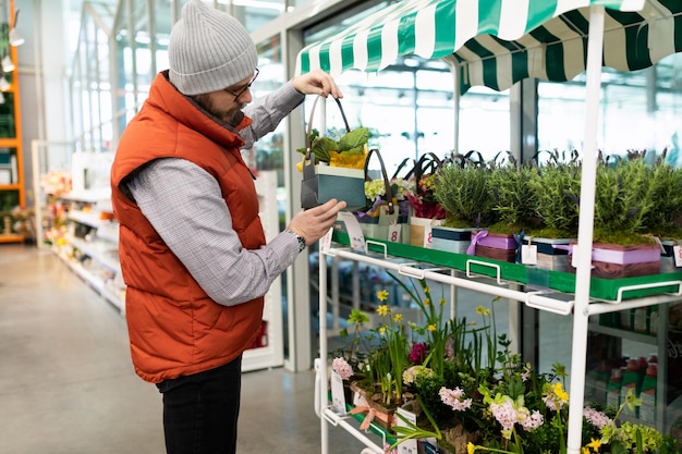 Um homem em uma loja de flores escolhe um vaso de plantas para sua casa