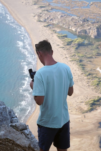 Foto um homem em uma montanha fotografa uma praia de iztuzu no mar mediterrâneo