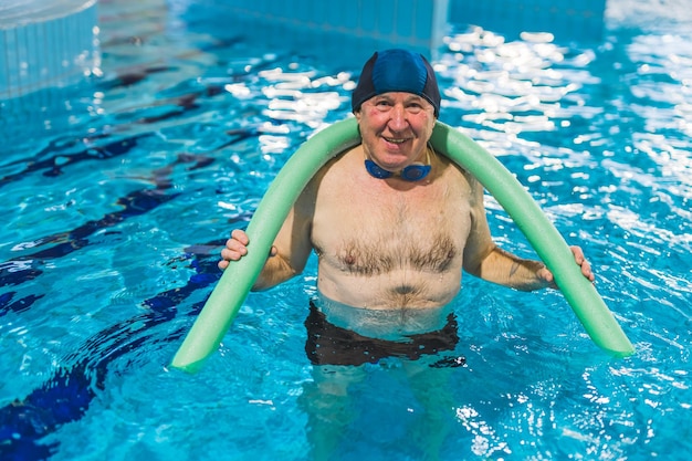 Um homem em uma piscina vestindo um colete salva-vidas e um colete salva-vidas.