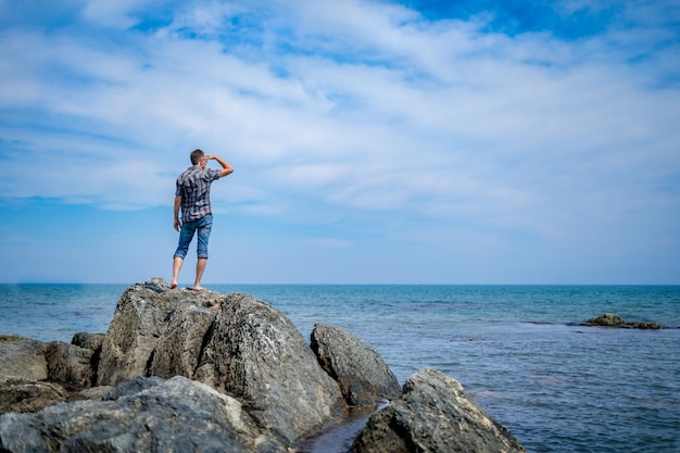 Foto um homem em uma praia rochosa olha para longe