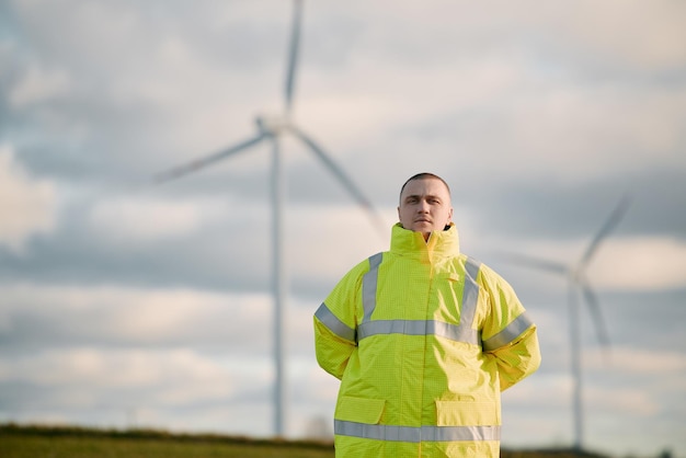 Um homem engenheiro está parado em um campo de turbina eólica com um belo fundo do céu Conceito de futuro sustentável