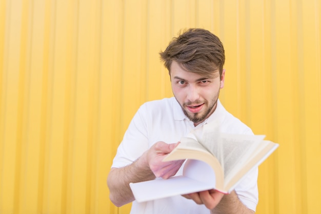 Um homem engraçado percorre as páginas do livro em uma parede amarela.