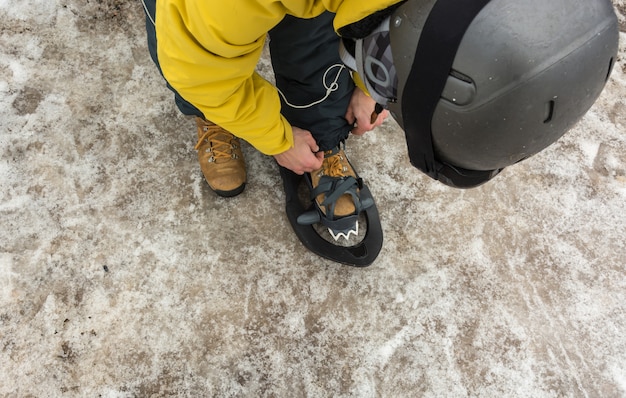 Um homem esportivo calçando suas raquetes de neve para iniciar uma excursão nas montanhas nevadas.