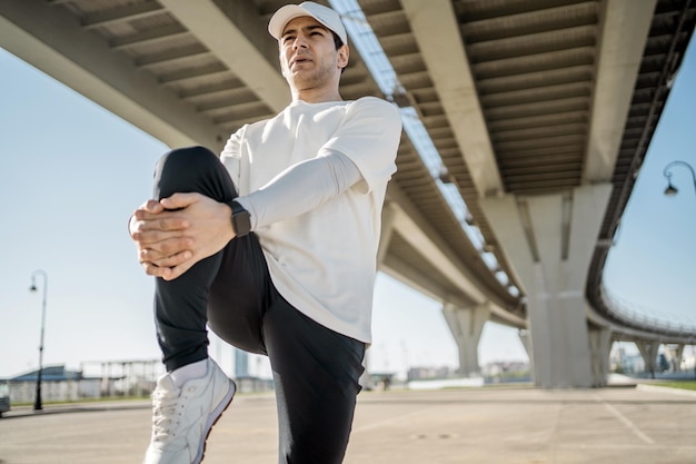 Um homem esportivo realiza um treino de fitness na cidade, roupas confortáveis, um relógio inteligente