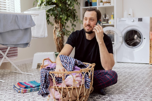 Um homem está ao telefone com a esposa enquanto faz as tarefas domésticas o telefonema