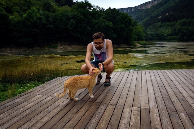 Um homem está brincando com um gato malhado vermelho doméstico