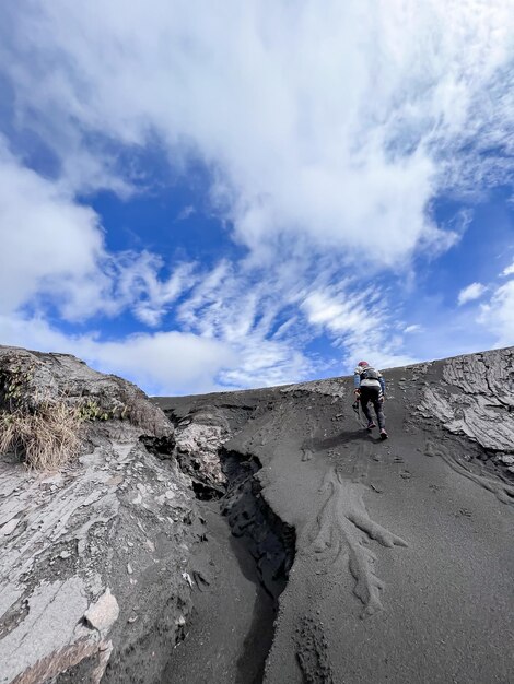 Foto um homem está caminhando em uma duna de areia em frente a um céu azul.