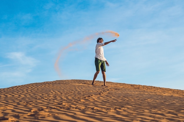 Um homem está chutando areia em um deserto vermelho. Conceito de respingo de raiva.