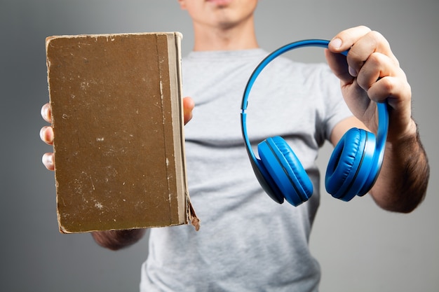 Foto um homem está com um livro e fones de ouvido. áudio-livro