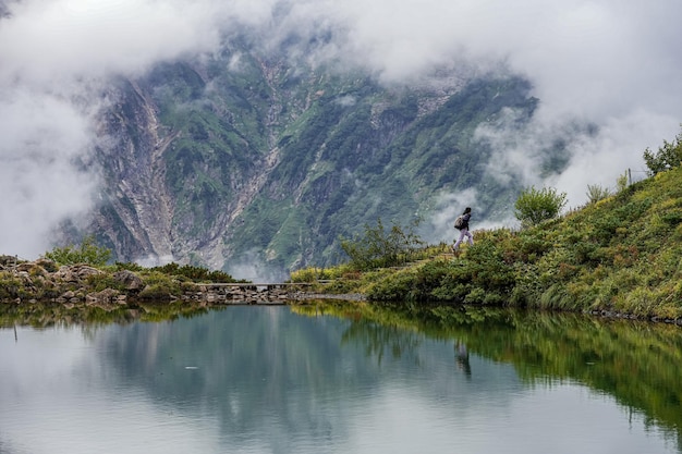 Foto um homem está de pé em uma montanha com um lago no fundo