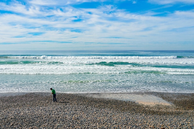 Um homem está em uma praia em frente ao oceano.