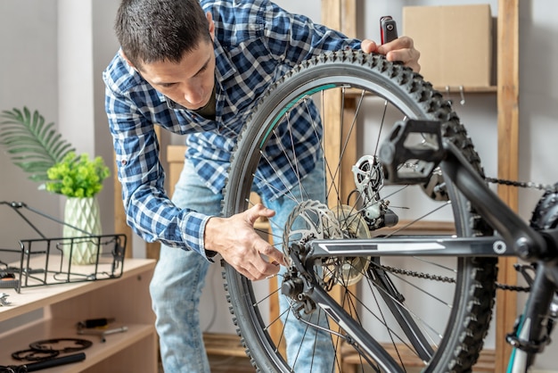 Um homem está fazendo manutenção em sua mountain bike. conceito de consertar e preparar a bicicleta para a nova temporada