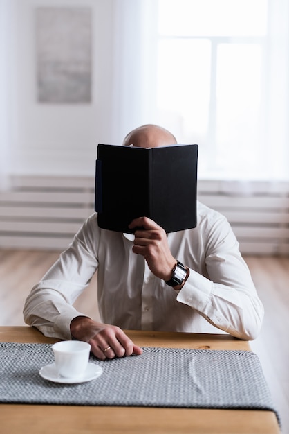 Um homem está lendo algo em um caderno preto. O conceito de freelancer, trabalho no escritório