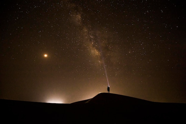 Um homem está no deserto sob uma via láctea brilhante.