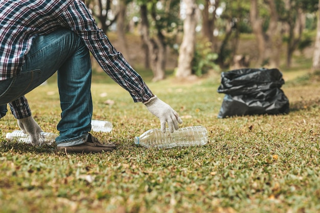 Foto um homem está pegando lixo em um parque não jogar lixo no lixo pode arruinar a beleza da área do jardim e também causar aquecimento global e prejudicar os animais conceito de limpeza em áreas públicas