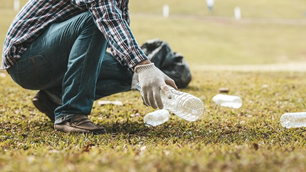 Um homem está pegando lixo em um parque não jogar lixo no lixo pode arruinar a beleza da área do jardim e também causar aquecimento global e prejudicar os animais Conceito de limpeza em áreas públicas