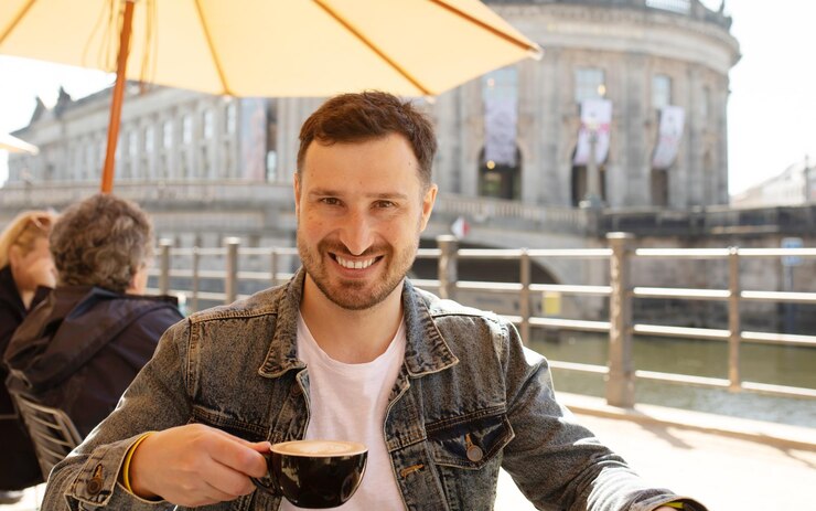 Um homem está sentado à mesa com uma xícara de café à sua frente