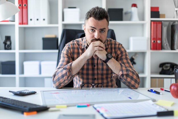 Um homem está sentado em uma mesa no escritório.