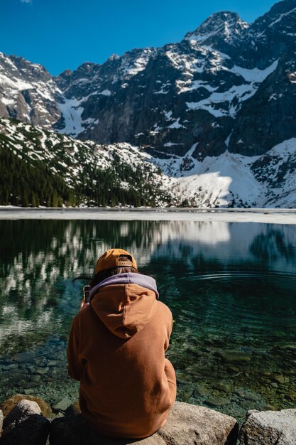 Um homem está sentado na margem das montanhas do lago Morskie Oko Tatras