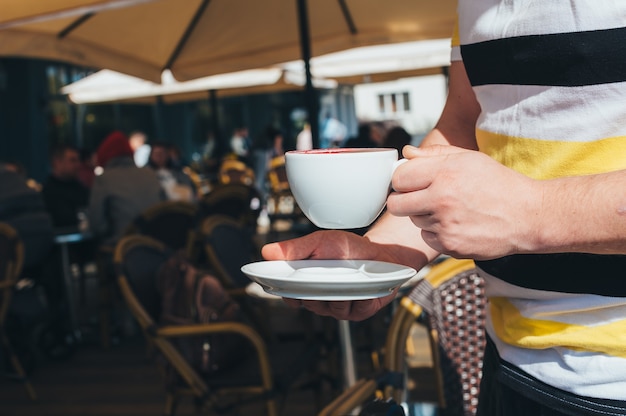 Um homem está tomando café em um restaurante ao ar livre.