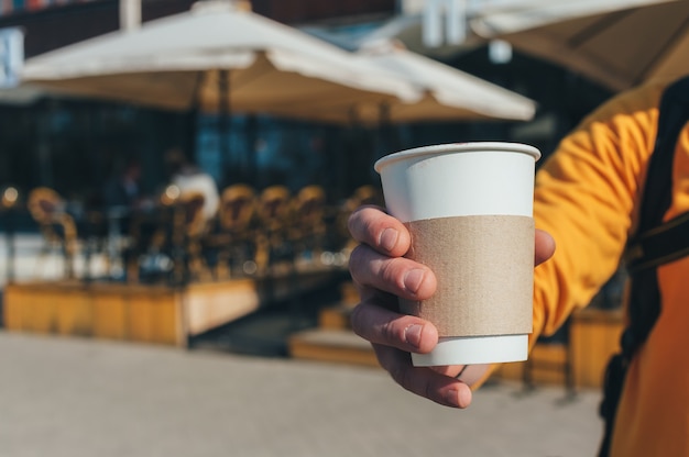 Um homem está tomando café em um restaurante ao ar livre.