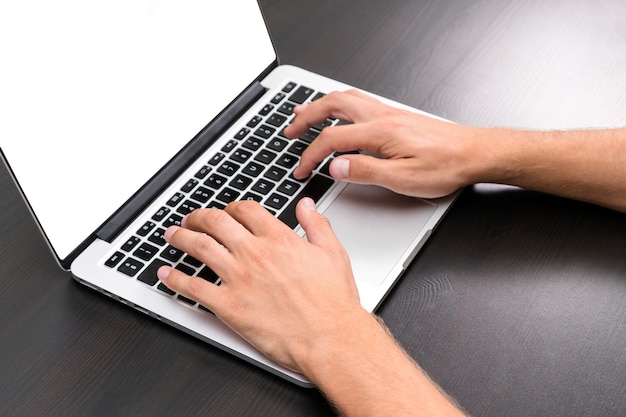 Um homem está usando um computador laptop na mesa de madeira vintage.