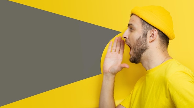 Um homem estiloso em um fundo amarelo grita em um megafone invisível. um lugar para o seu texto ou lo