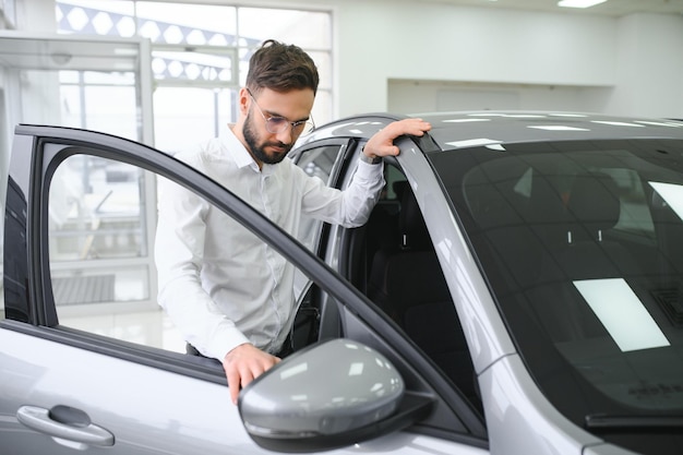 Um homem examina um carro em uma concessionária de carros