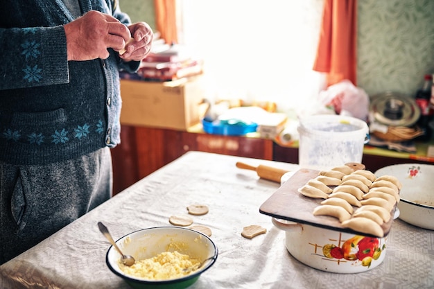 Foto um homem faz bolinhos em uma aldeia ucraniana vareniki com queijo cottage salgado caseiro