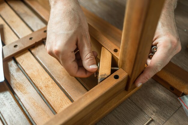 Um homem faz madeira Um mestre com ferramentas repara móveis Reparação de móveis Pai coleciona móveis em casa Restauração de móvel doméstico