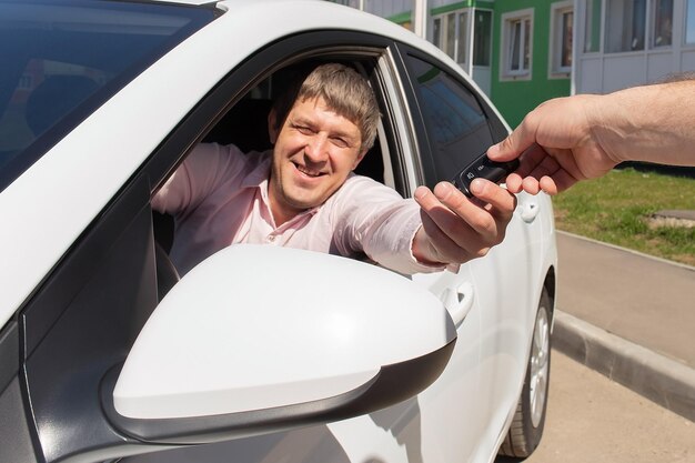 Um homem feliz e sorridente recebe as chaves de um carro novo Comprando e vendendo um carro