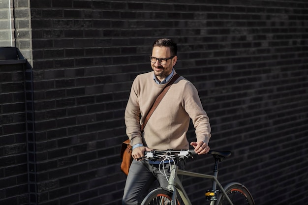 Um homem feliz empurrando uma bicicleta para cima na rua