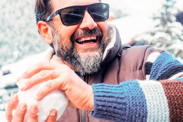 Um homem feliz se divertindo jogando bola de neve com amigos ou esposa Retrato de atividade férias de inverno atividade de lazer atitude de homem adulto jovem e brincalhão pessoas alegres