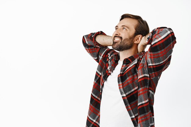 Um homem feliz sorridente deitou-se e olhou para cima com cara satisfeita Cara relaxando com as mãos atrás da cabeça pose despreocupada fundo branco