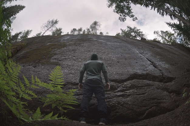 Um homem fica em frente a uma parede de granito natural Vista traseira Homem e obstáculo