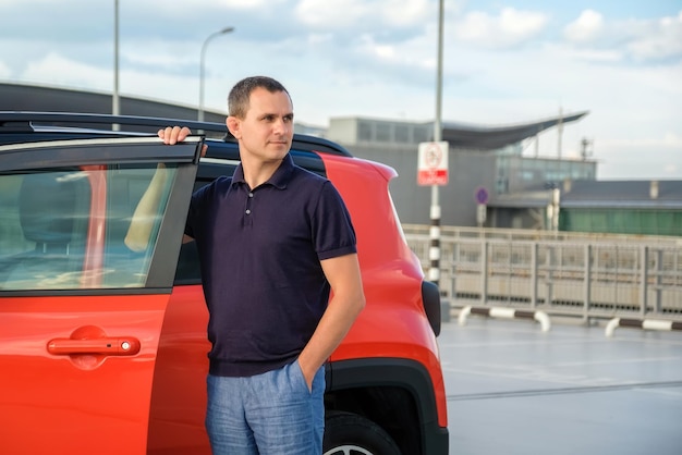 Um homem fica perto de seu carro no estacionamento