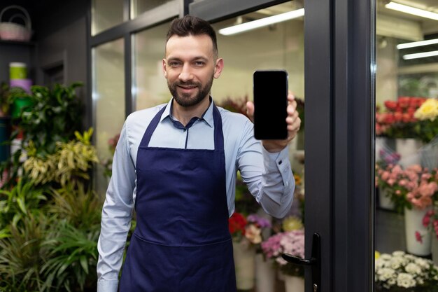 Um homem florista ao lado da geladeira com flores e buquês não fica e demonstra o