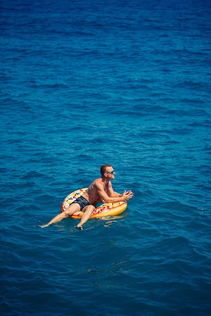 Um homem flutua em um anel inflável no mar com água azul Férias no mar em um dia ensolarado Conceito de férias na Turquia