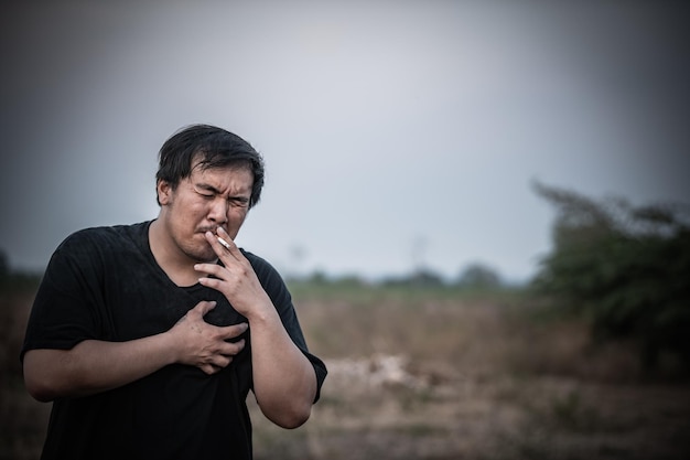 Um homem fumando em um campo com um coração no peito.